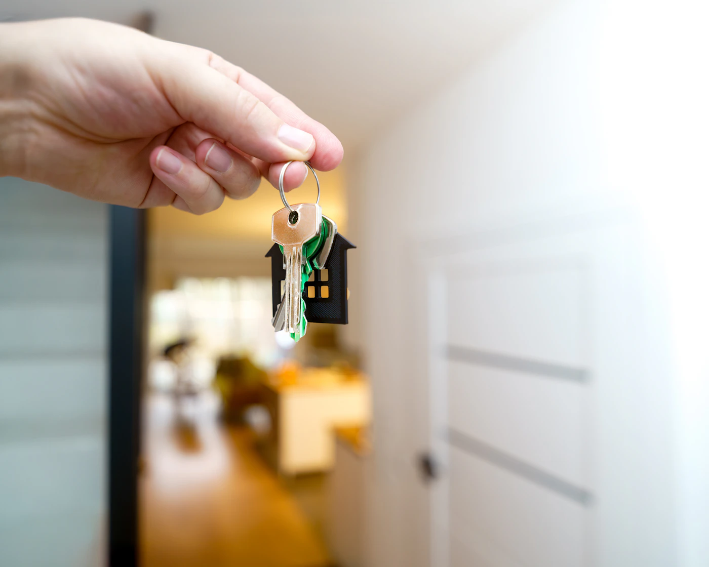 A hand holding keys beside the entrance to a home