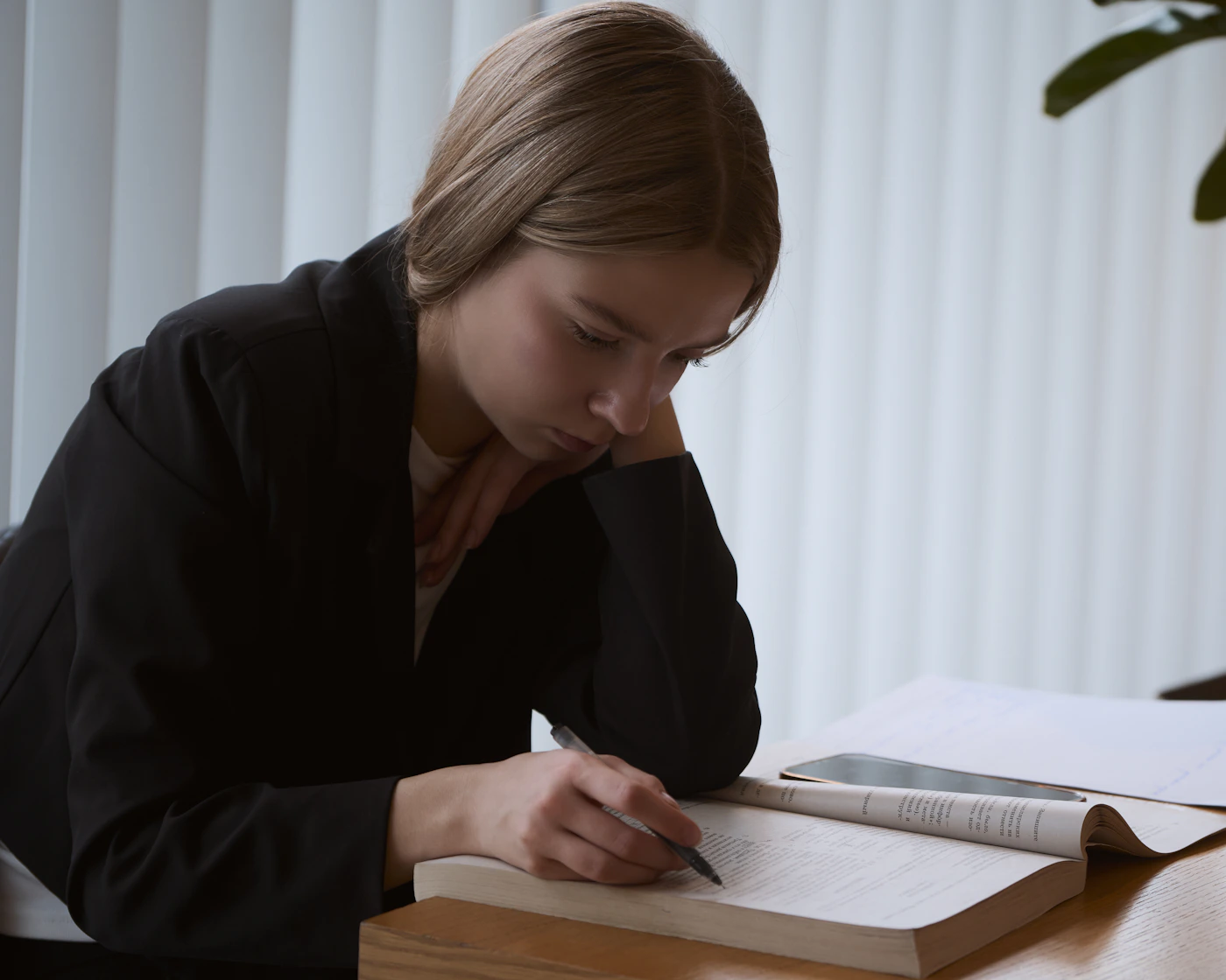A young adult reading and making notes at a desk