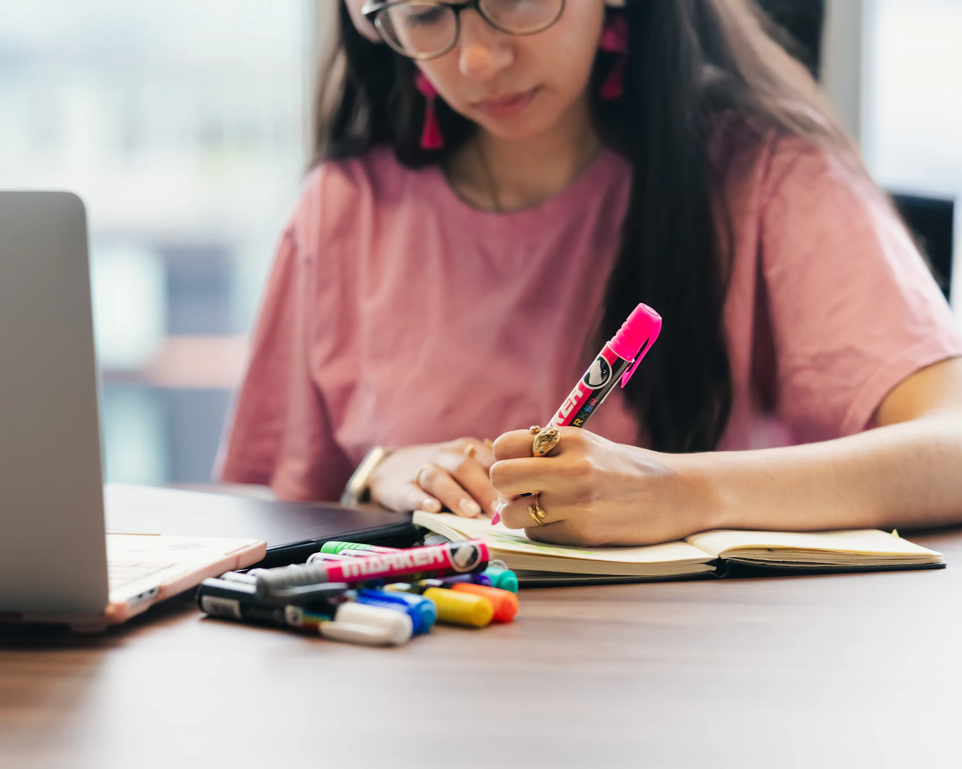 A young adult writing notes beside a laptop