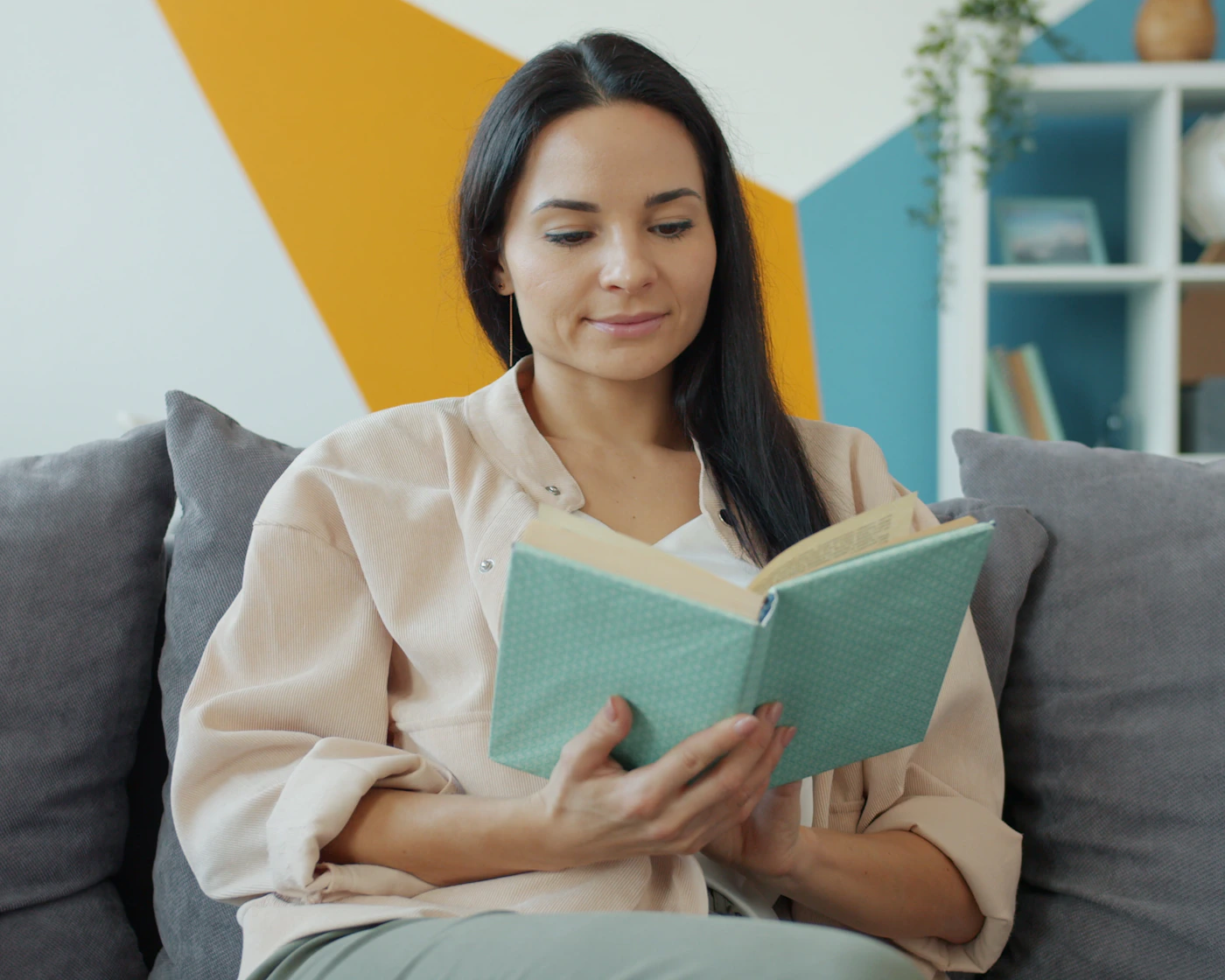 A young adult reading and relaxing on a sofa at home