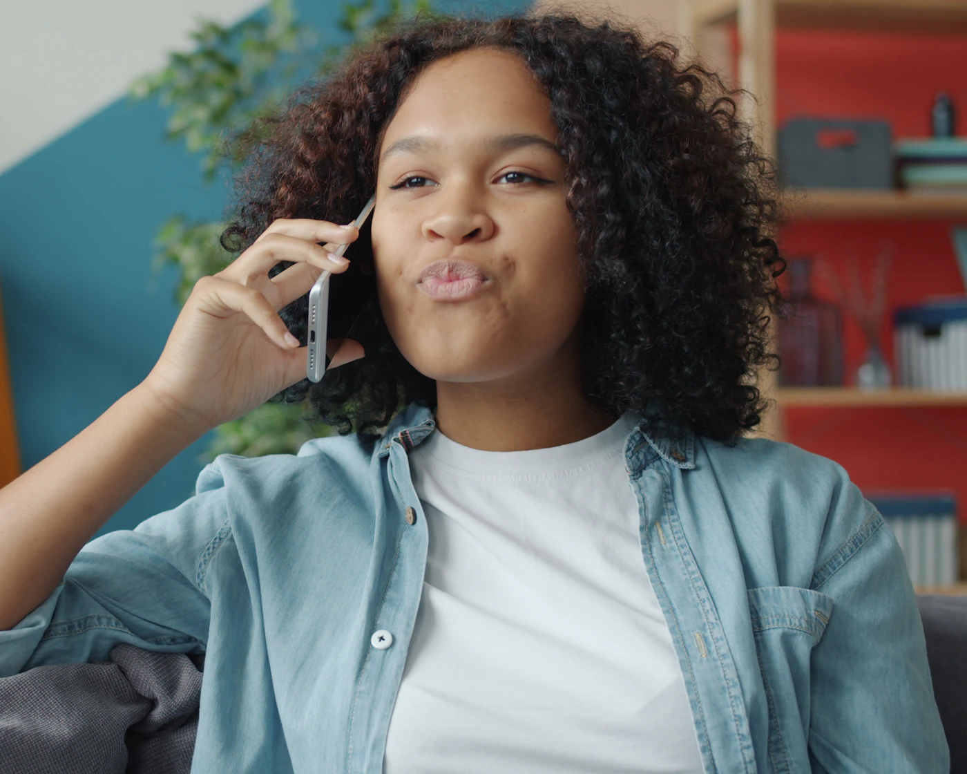 A young adult smiling while talking on the phone at home