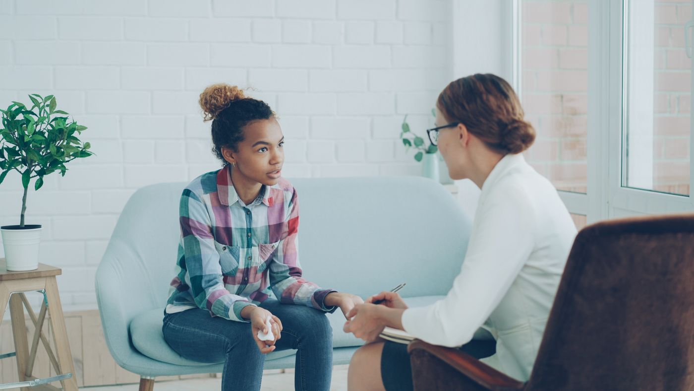 A young person speaking with a support professional in a bright seating area